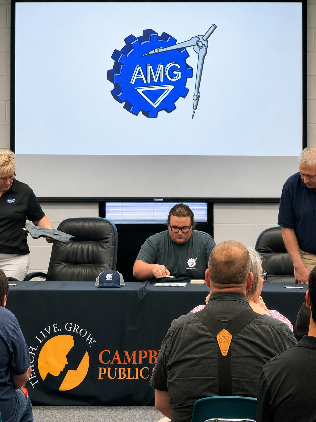 Joey Copes seated at the signing table with the AMG logo projected behind him during the CTE Signing Day ceremony.